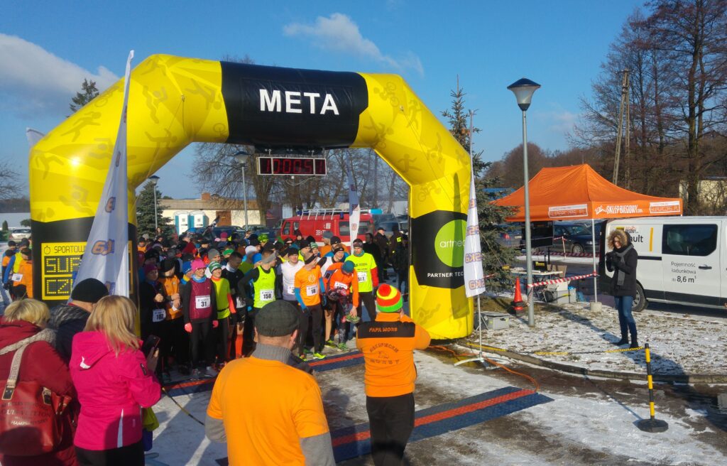 Biegacze stoją przy mecie zawodów biegowych.