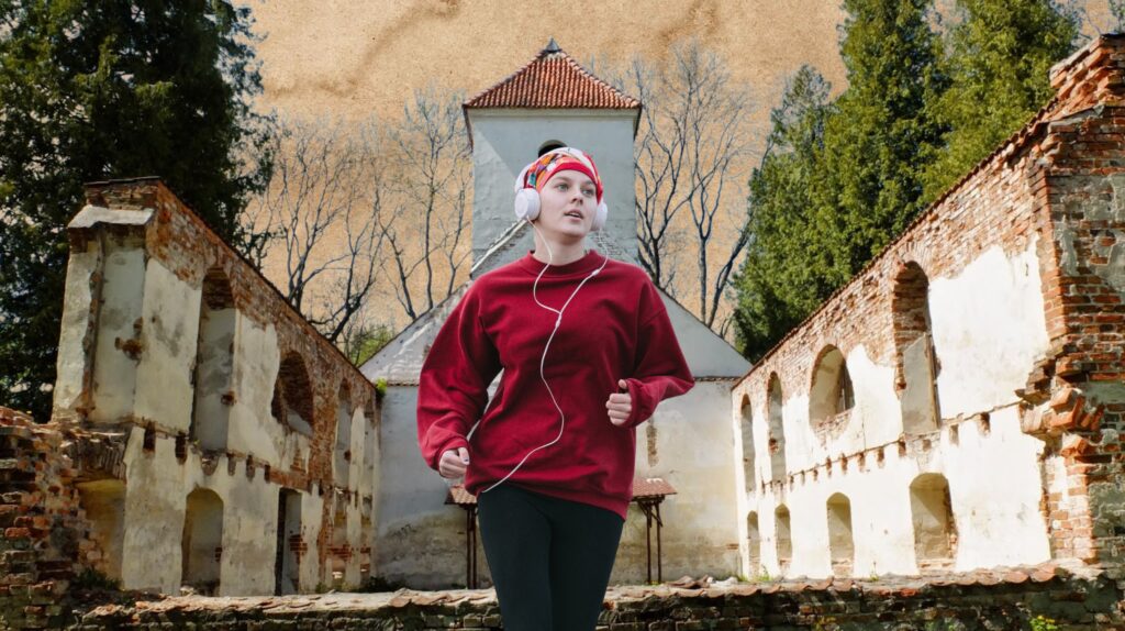 Biegająca kobieta w słuchawkach w ruinach.