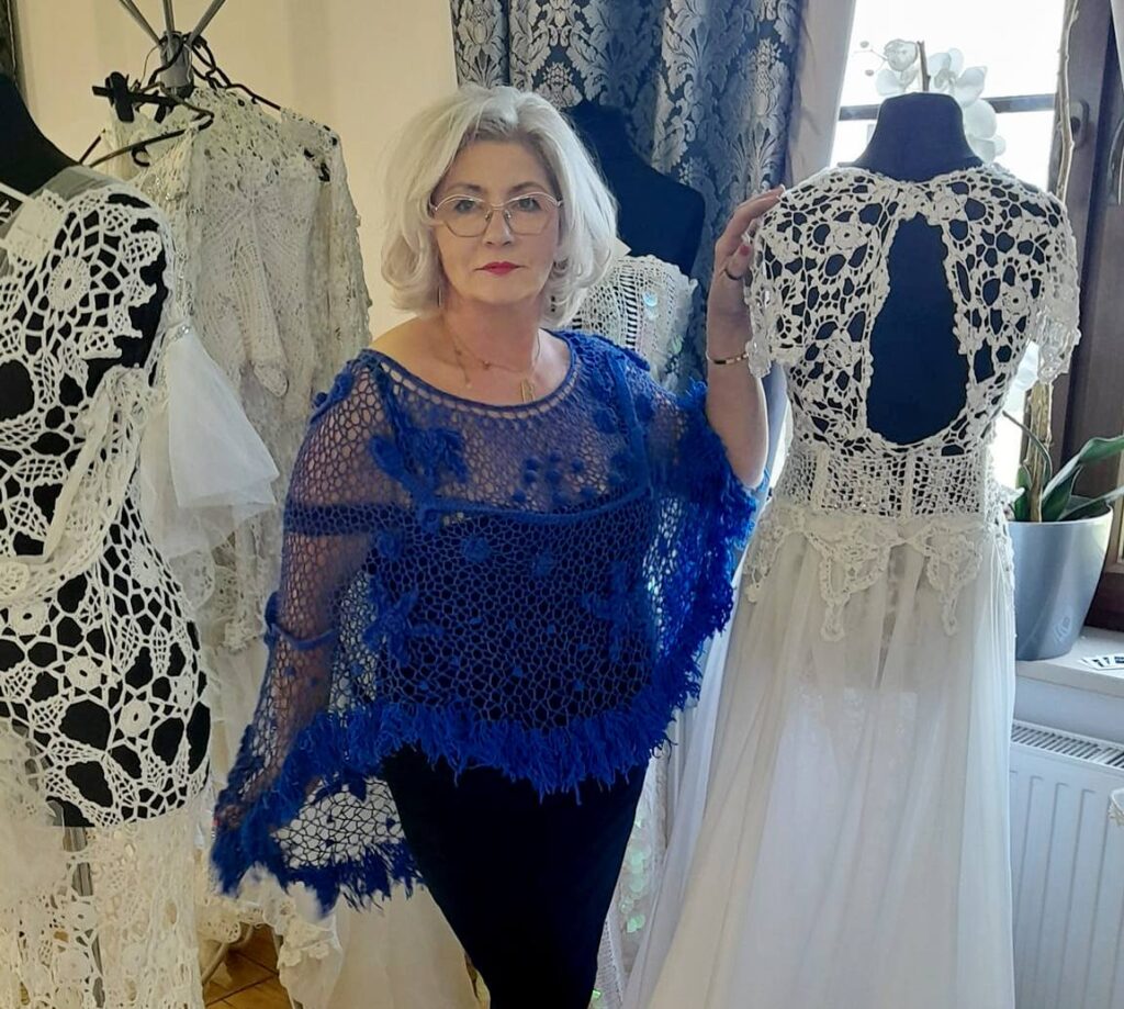 Kobieta w niebieskim swetrze obok sukni na manekinie.