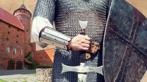 Rycerz w zbroi trzymający miecz i tarczę.