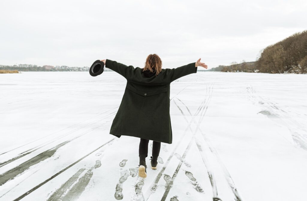 Osoba w zimowym płaszczu na zamarzniętym jeziorze.