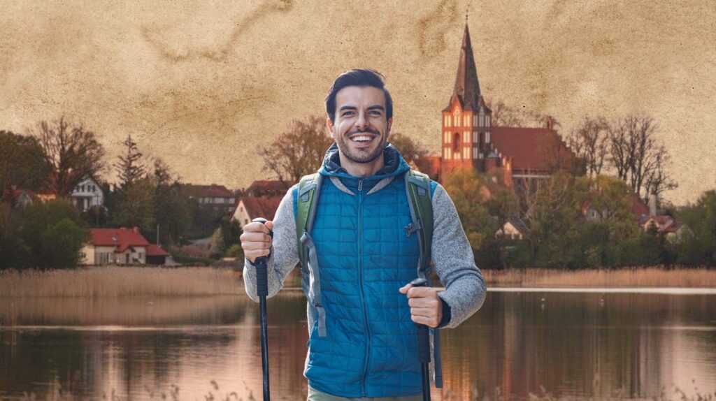 Mężczyzna na tle jeziora z wioskami i kościołem.