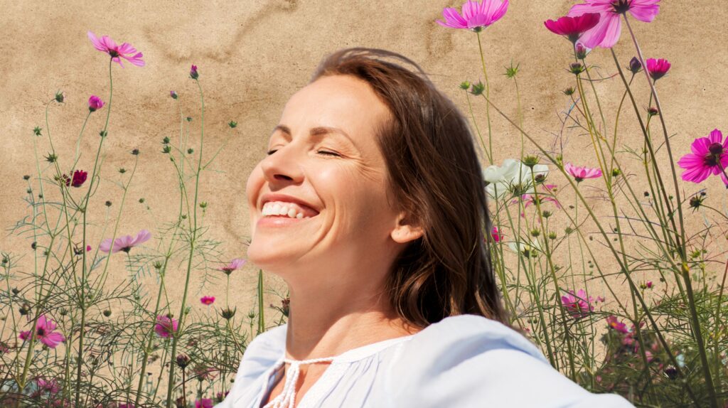 Uśmiechnięta kobieta wśród kwiatów.