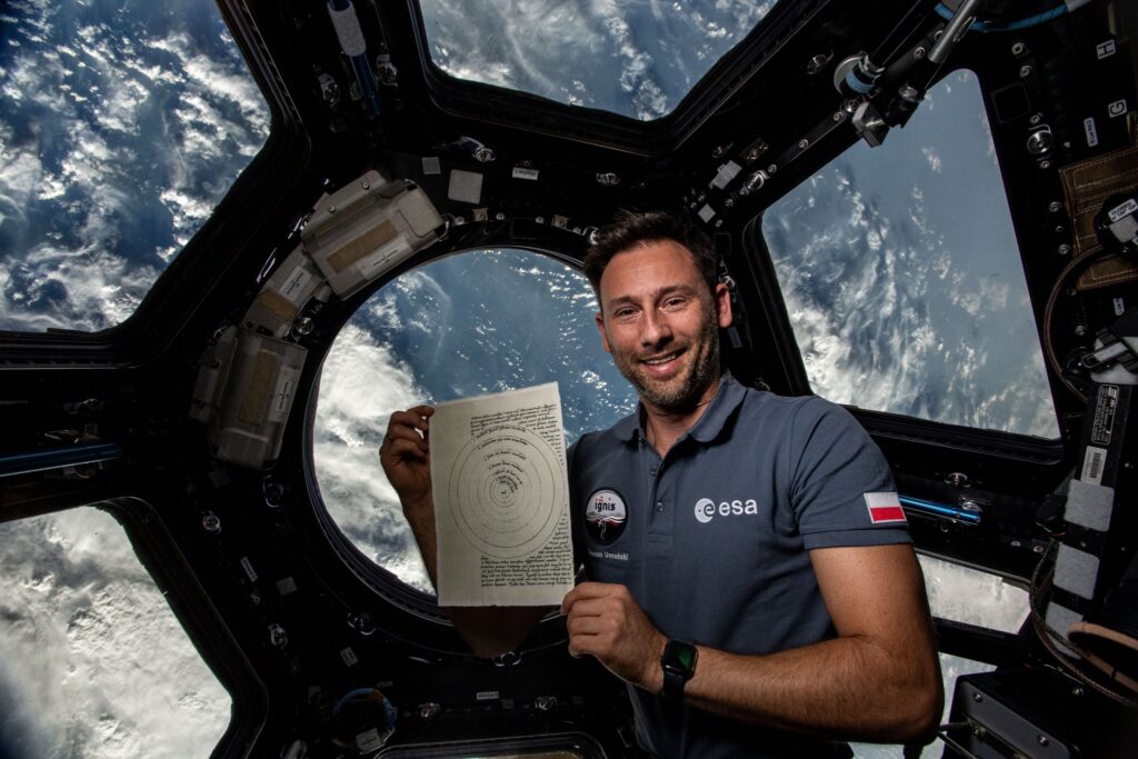 Astronaut trzyma kartkę w przestrzeni kosmicznej