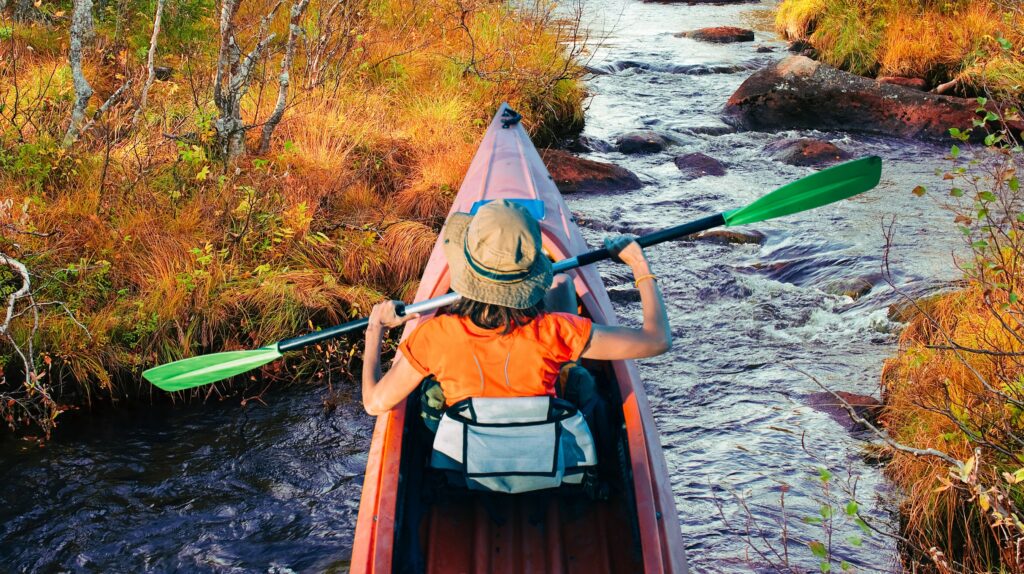 Osoba w kajaku płynąca przez strumień.