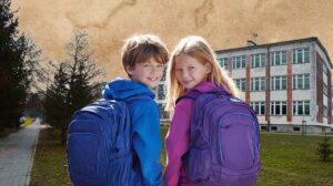 Dzieci z plecakami na tle szkoły