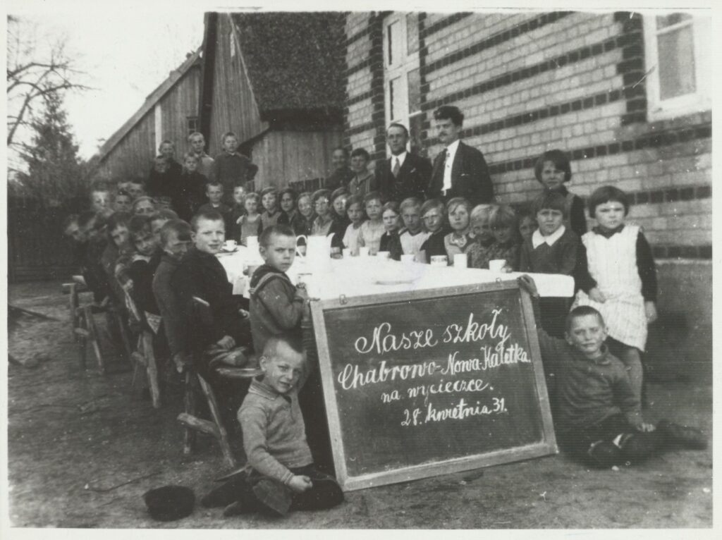 Grupa dzieci i dorosłych przy stole na zewnątrz