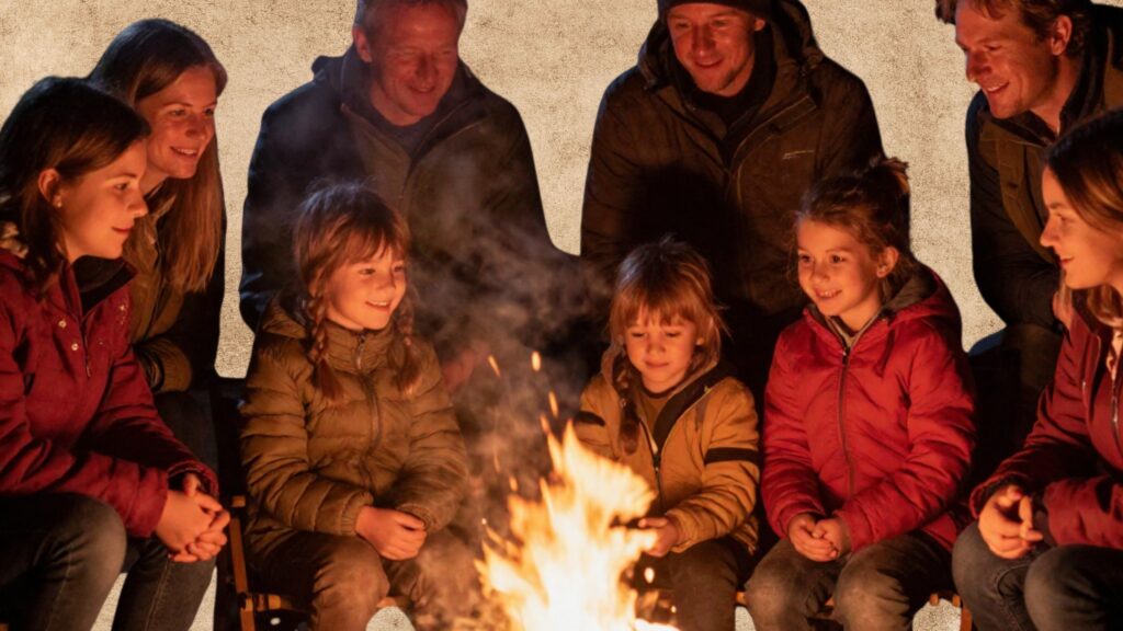 Zdjęcie grupy dorosłych i dzieci siedzących wieczorem przy wspólnym ognisku