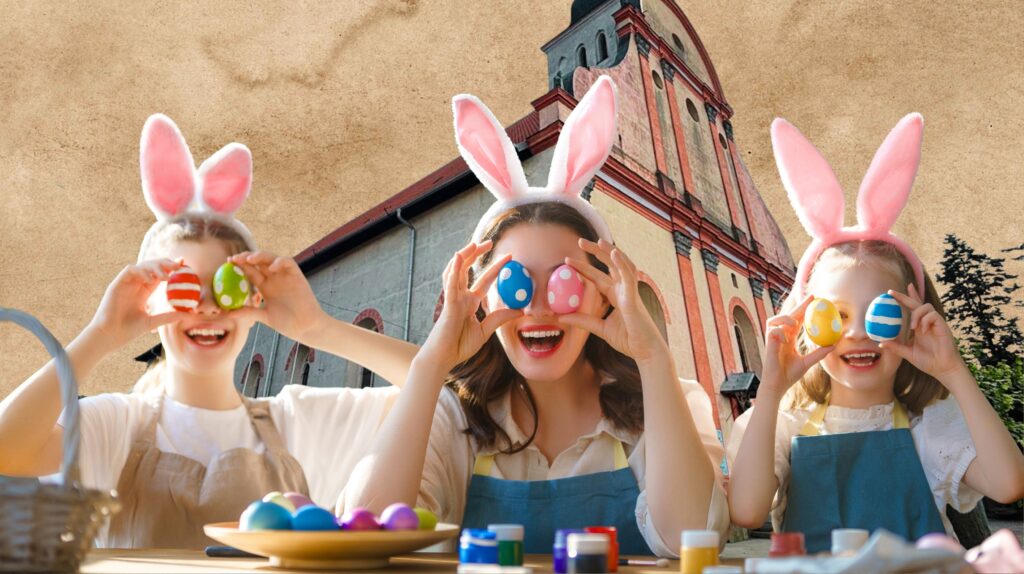 Dwie dziewczynki i kobieta w uszach królika trzymają kolorowe pisanki.