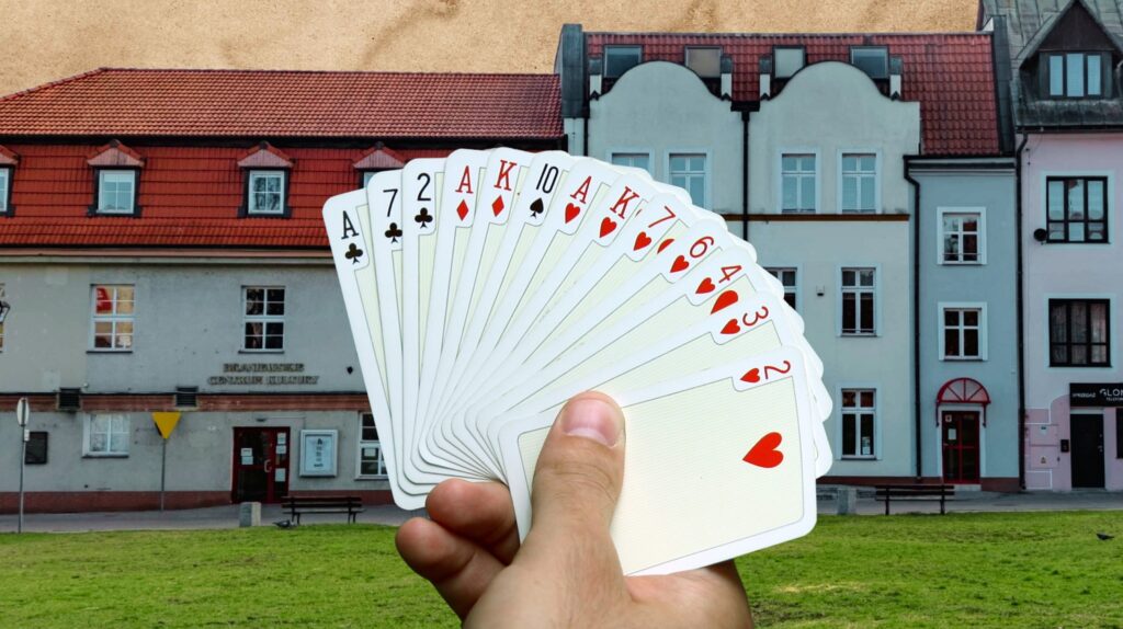 Karta do gry w ręce na tle budynku.