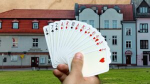 Karta do gry w ręce na tle budynku.