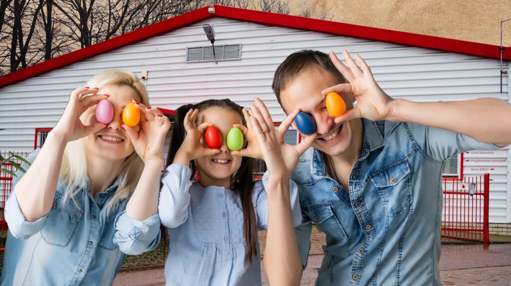 Rodzina trzyma kolorowe pisanki przed sobą.