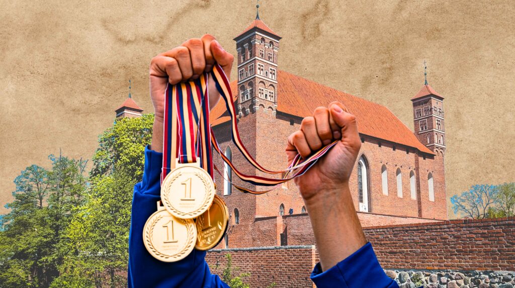 Osoba trzymająca złote medale przed historycznym budynkiem.