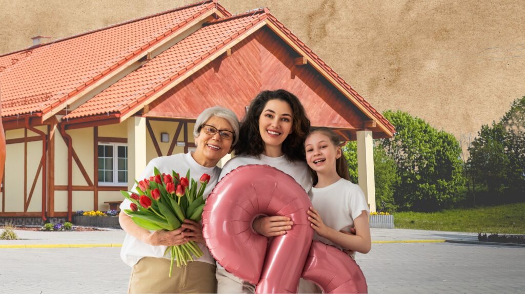 Trzy osoby trzymają bukiet tulipanów i balon w kształcie liczby 2 przy nowoczesnym budynku.