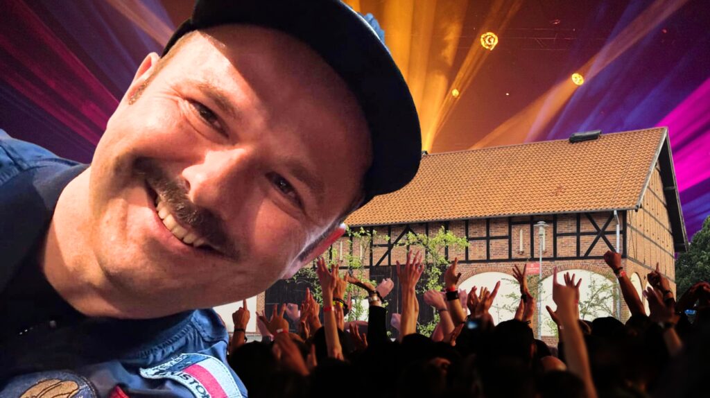 Uśmiechnięty mężczyzna z koncertem w tle.