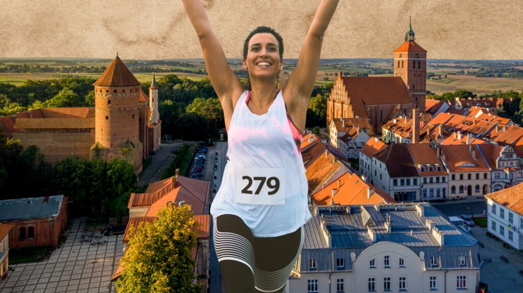 Radosna biegaczka z numerem 279 na tle miasta i zamku.