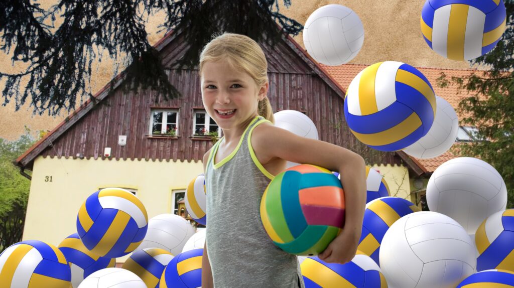Dziecko trzymające piłkę w otoczeniu piłek siatkowych.