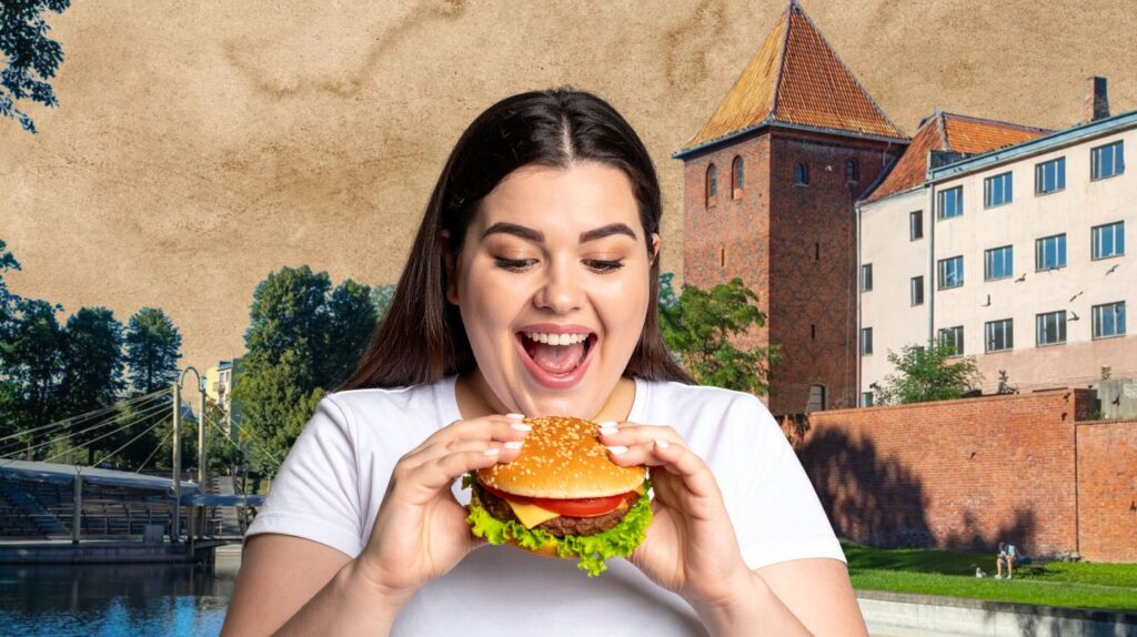 Kobieta trzymająca hamburgera z zachwytem.