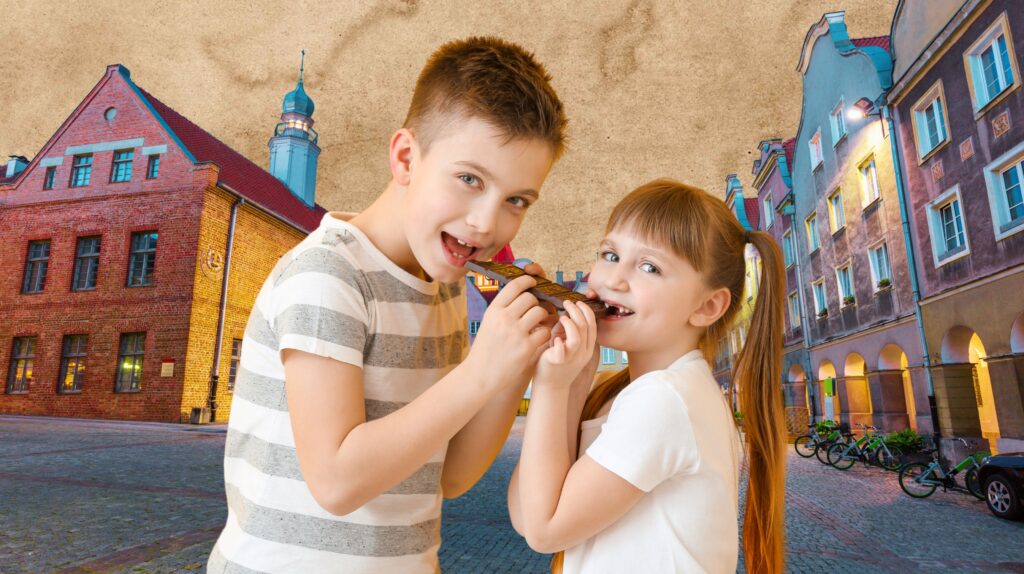 Dwoje dzieci dzieli się czekoladą na tle uliczki.