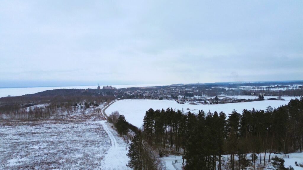 Widok na zimowy krajobraz z miasteczkiem w tle.
