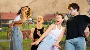 Cztery osoby tańczące na tle krajobrazu.