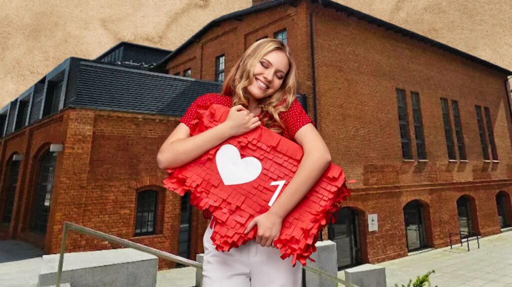 Kobieta trzyma czerwoną piniatę w kształcie serca.