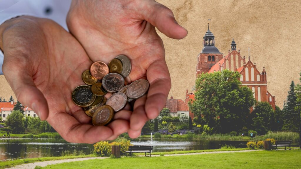 Ręka trzymająca monety z widokiem na kościół.