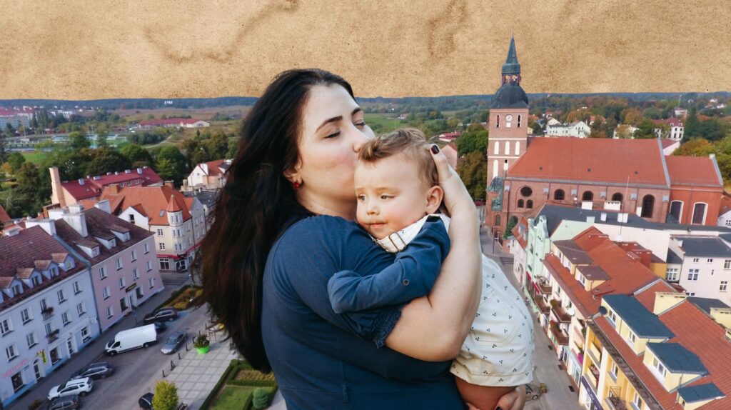 Kobieta trzymająca dziecko w objęciach na tle miasta.