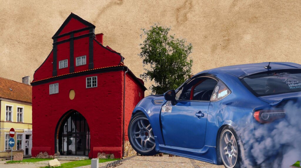Niebieski samochód sportowy skaczący obok czerwonego budynku.