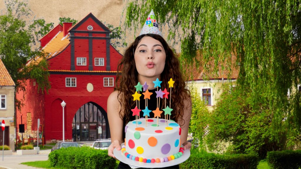 Kobieta trzymająca urodzinowy tort z kolorowymi gwiazdkami.