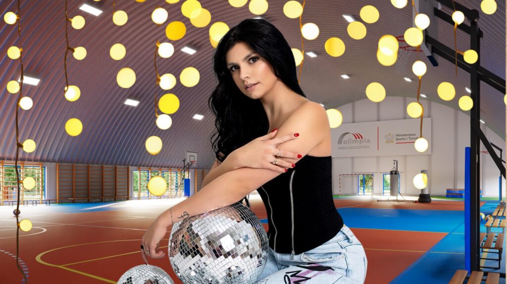 Młoda kobieta z lustrem disco w hali sportowej.