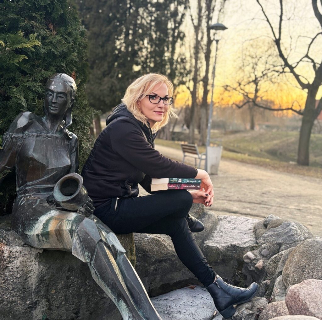 Kobieta siedząca obok brązowej statuy w parku.