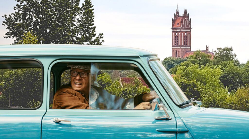 Starszy mężczyzna w niebieskim samochodzie.