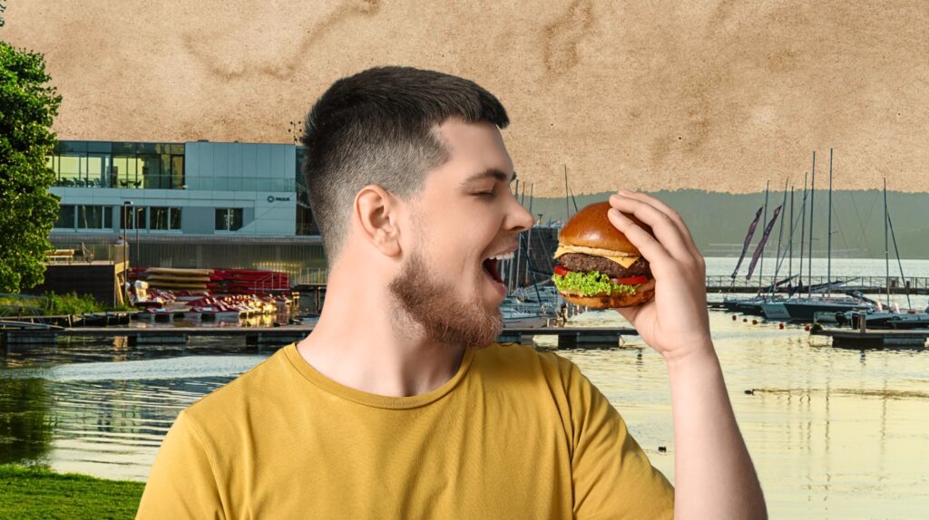 Mężczyzna trzyma hamburgera w pobliżu przystani.