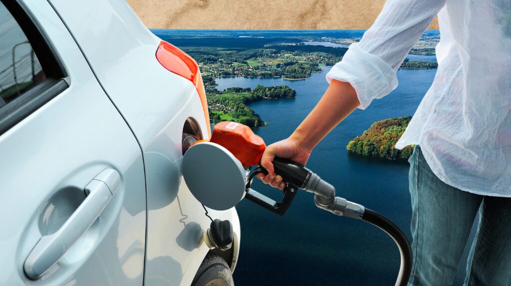 Osoba tankująca samochód na tle jeziora.