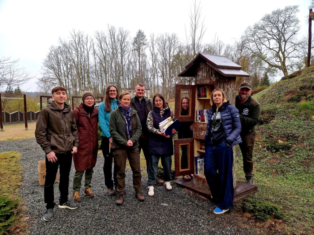 Grupa ludzi przy regale z książkami na świeżym powietrzu.