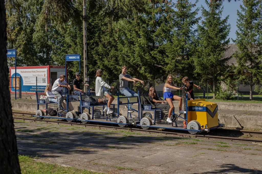 Grupa młodych ludzi na wózku wzdłuż torów kolejowych.