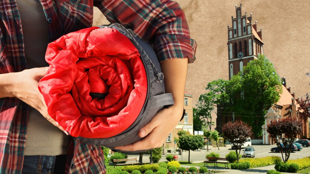 Osoba trzyma zrolowany czerwony śpiwór.