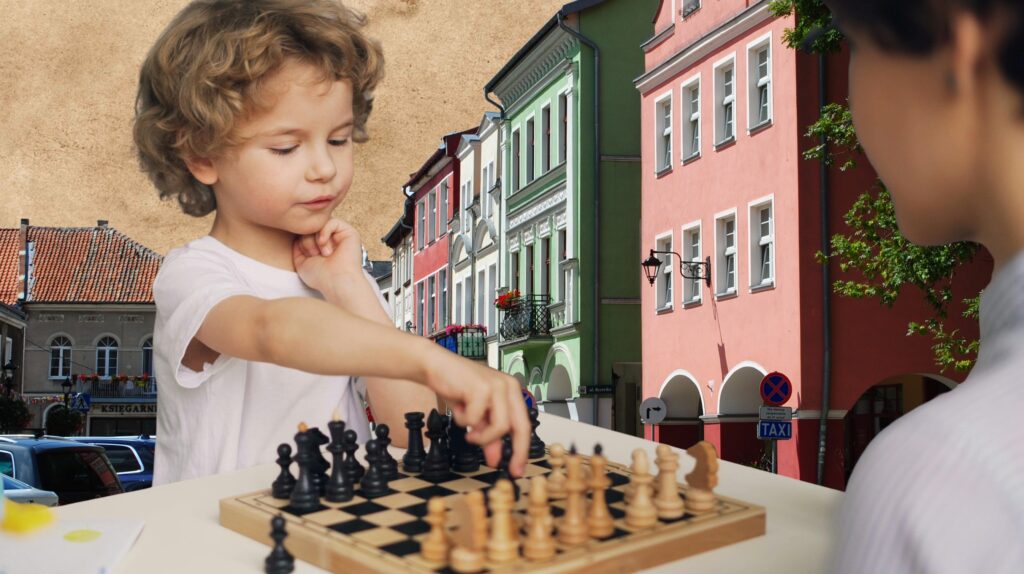 Dziecko gra w szachy przy kolorowych budynkach.