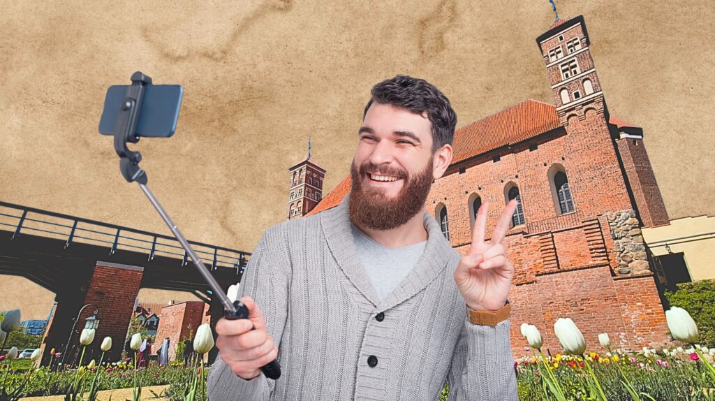 Mężczyzna robi selfie z uśmiechem w tle historyczny budynek.