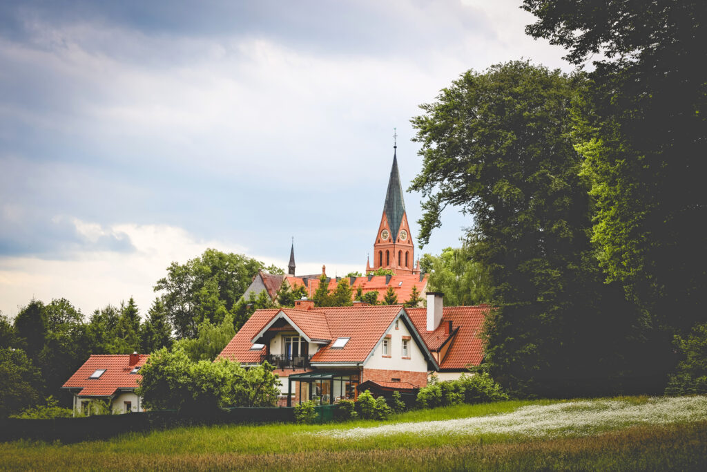 Widok na domy i kościół w zielonym otoczeniu.