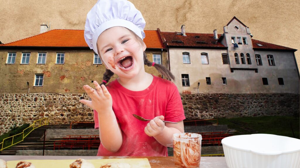 Uśmiechnięta dziewczynka w kuchni z czekoladą na buzi.