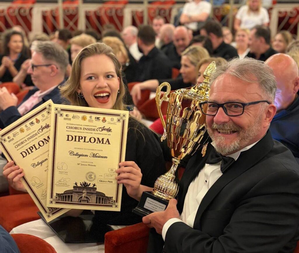 Osoba z dyplomami i trofeum na wydarzeniu