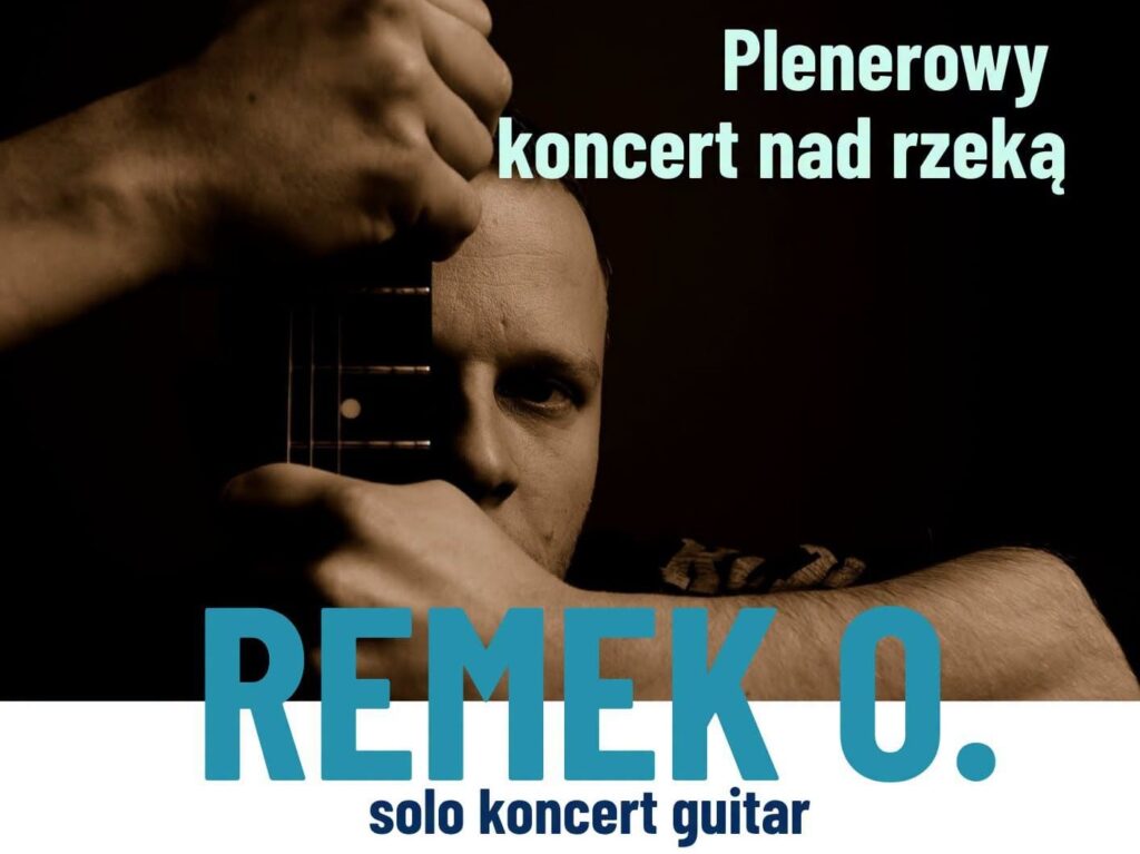 Mężczyzna grający na gitarze podczas koncertu na świeżym powietrzu.
