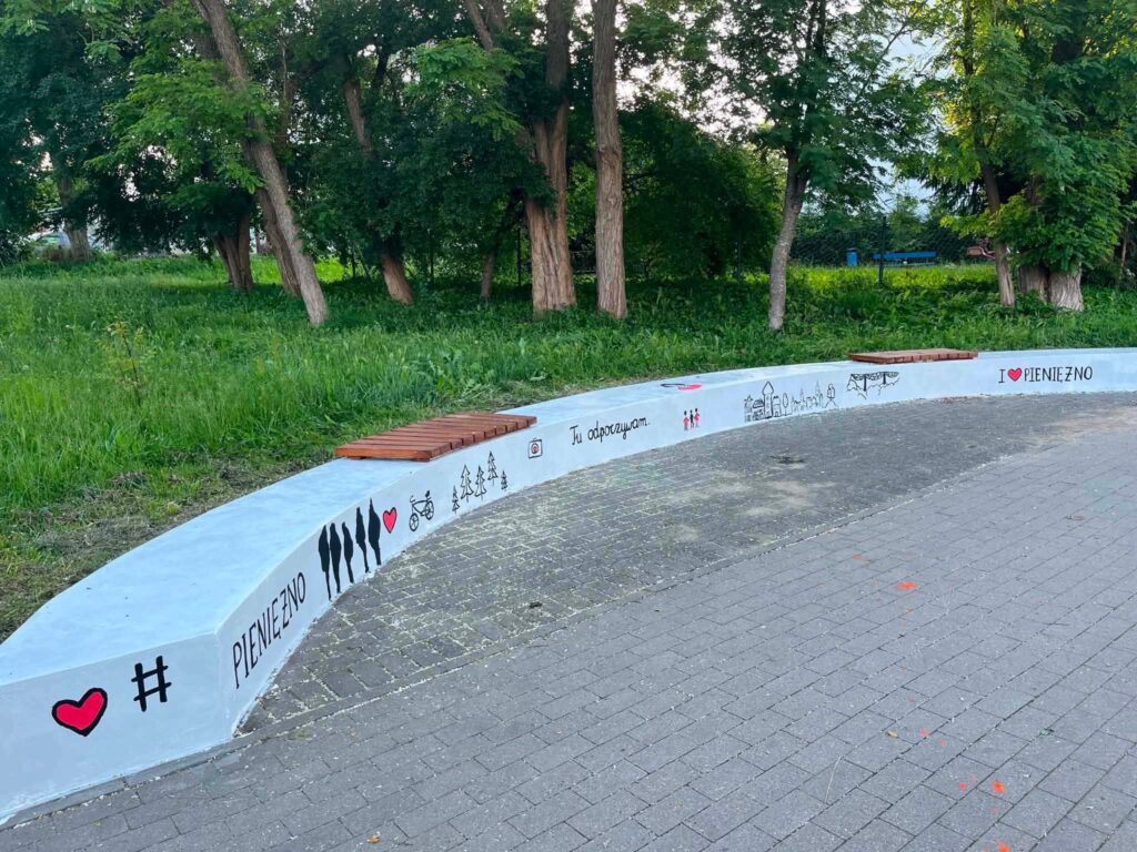 Mur z muralem i ławkami w parku.