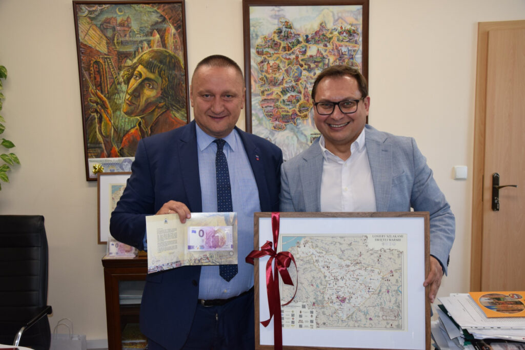 Dwóch mężczyzn trzyma mapę i banknot.