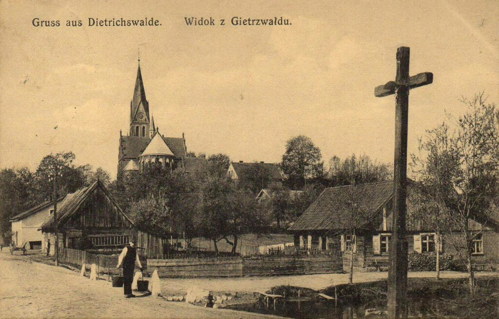 Widok na wieś Dietrichswalde z drewnianymi domami i kościołem.