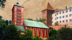Widok na czerwoną, gotycką katedrę z wieżami i zielonym dachem, otoczoną drzewami.