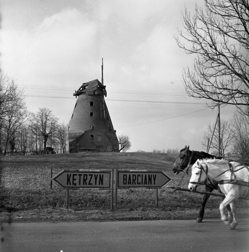 Stary młyn z końmi przejeżdżającymi obok