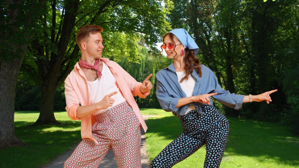 Dwóch tancerzy w kolorowych ubraniach pozującym na tle parku.